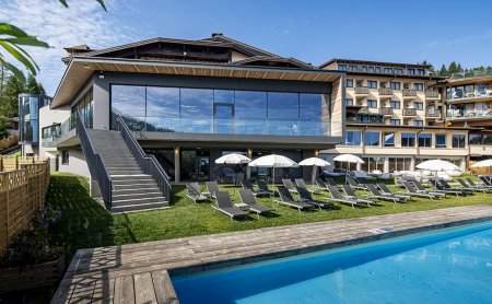Liegestühle und Sonnenschirme am Pool vor moderner Hotelfassade