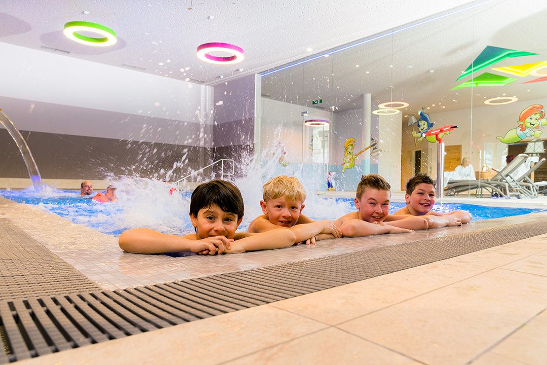 Kinder plantschen lachend im bunten Indoorpoolbereich