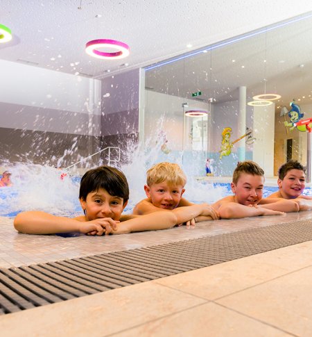 Kinder plantschen lachend im bunten Indoorpoolbereich