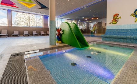 Kinderbecken mit grüner Rutsche und buntem Licht im Indoorbereich