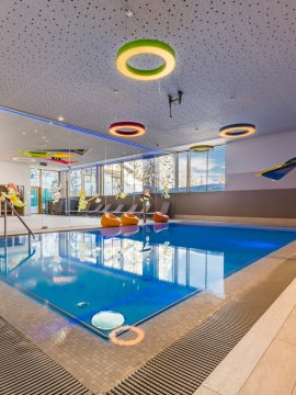 Indoorpool mit Wasserspiel, Rutsche und bunten Deckenelementen