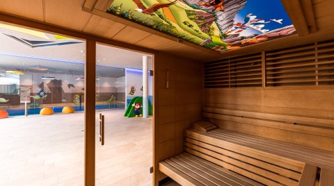 Holzsauna mit Glasfront und bunter Kinderdecke beim Indoorpool