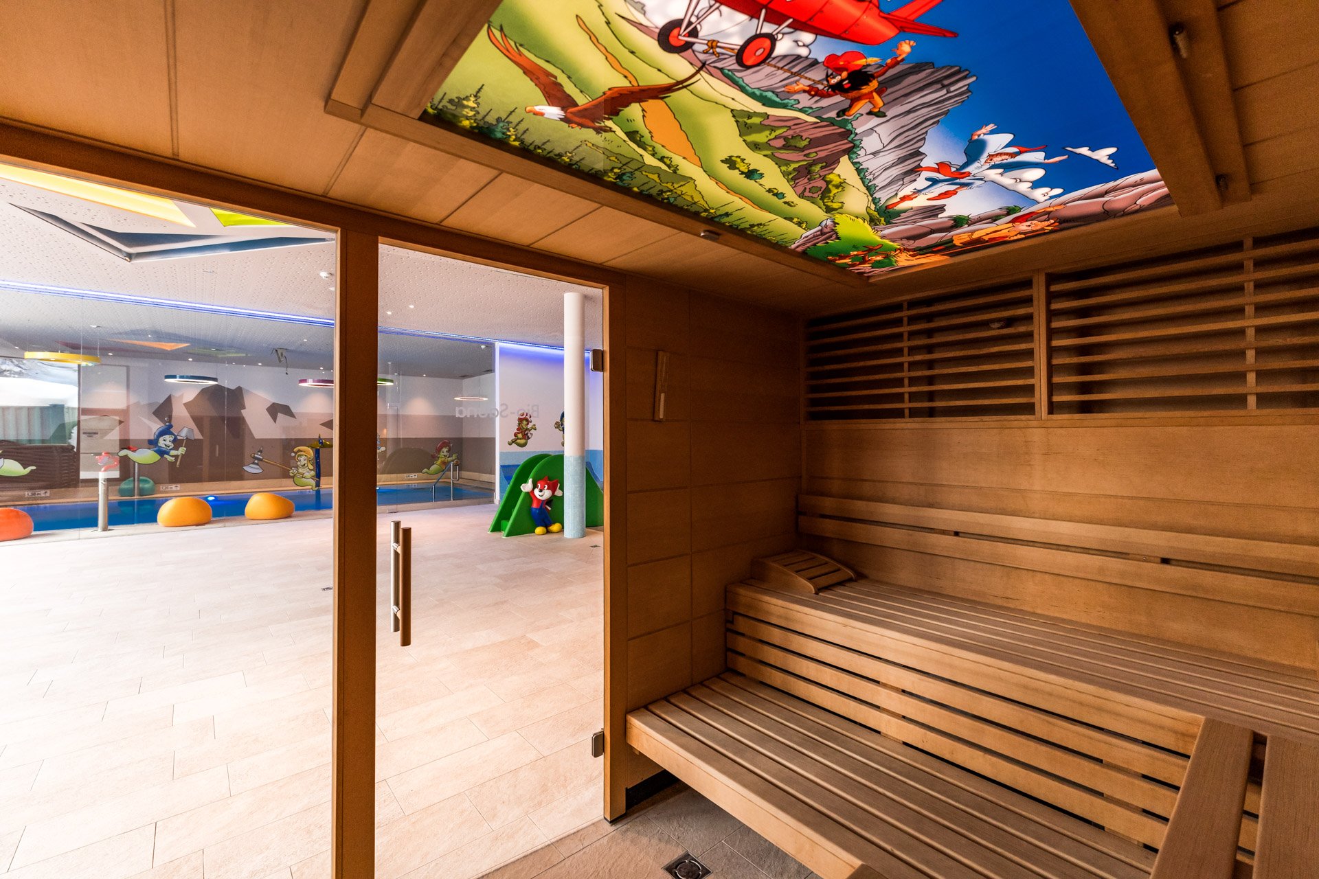 Holzsauna mit Glasfront und bunter Kinderdecke beim Indoorpool