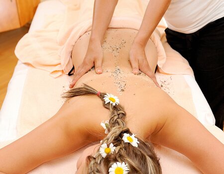 Dame wird mit Gartnerkofel Peeling bei einer Massage behandelt