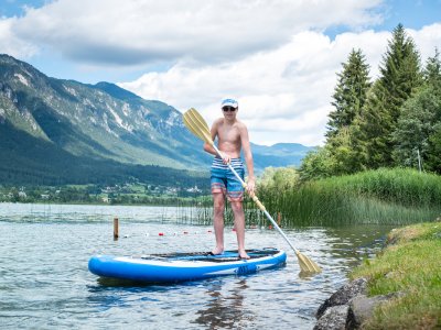 Stand-up paddler near shore with mountain view and reeds