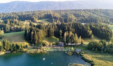 Aerial view of the lake with surrounding forest and sunbathing lawn