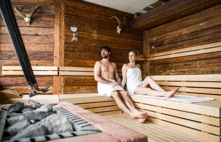 Paar entspannt in rustikaler Sauna mit Holzverkleidung