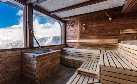 Sauna mit Holzverkleidung und Panoramafenster auf Schneelandschaft