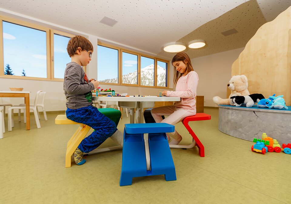 Mädchen und Junge spielen mit Lego am Tisch