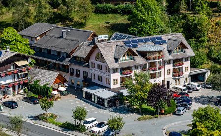 Hotelanlage mit Solarpanels, umgeben von Bäumen und geparkten Autos