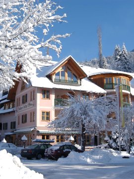Hotelgebäude im Winter mit verschneiten Bäumen und blauen Himmel