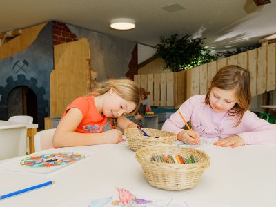 Zwei Mädchen malen am Tisch mit Buntstiften