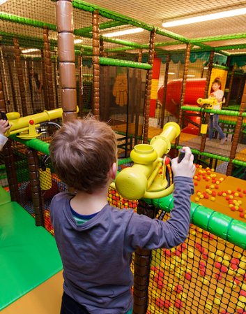 Kinder spielen mit Softball-Kanonen in bunter Indoor-Spielwelt