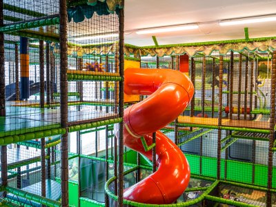 Großer Indoor-Spielturm mit roter Röhrenrutsche über mehrere Etagen