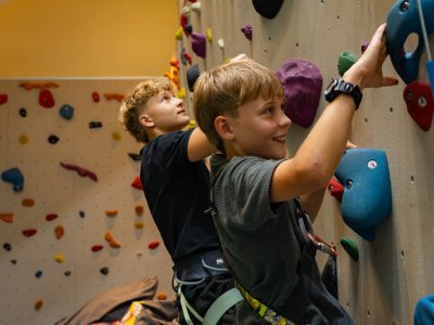 Zwei Jungen klettern an einer bunten Kletterwand in einer Halle