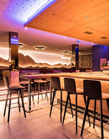 Moderne Hotelbar mit stimmungsvoller Beleuchtung und Bergpanorama