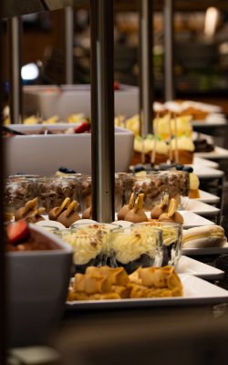 Close-up of various desserts on white plates arranged in a buffet line