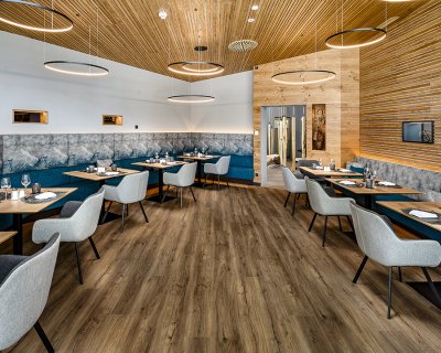 Geräumiges Restaurant mit Holzdecke, Designleuchten und Bergmotiv-Polsterung