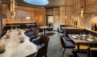 Exclusive wine lounge with natural wood table, designer lights and leather seating