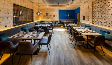 Stylish dining room with wood walls, skylight and set tables