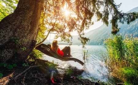 Frau entspannt in Hängematte am Seeufer im Sonnenuntergang