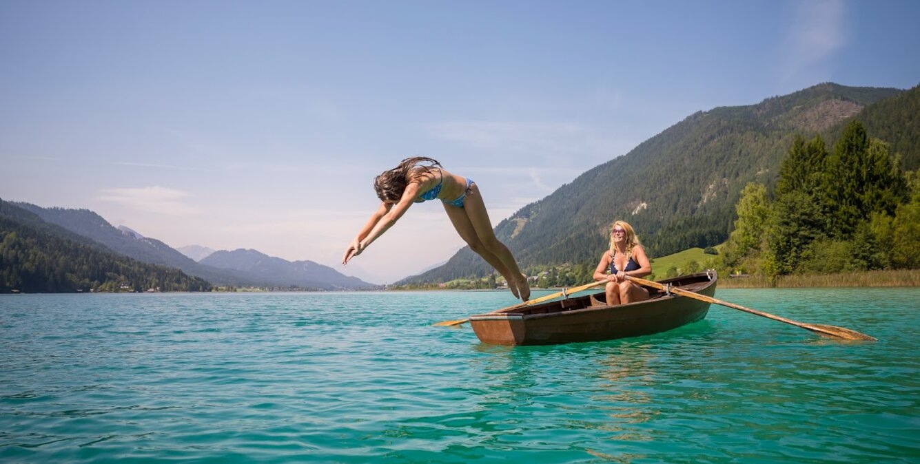 Mädchen springt vom Ruderboot ins Wasser