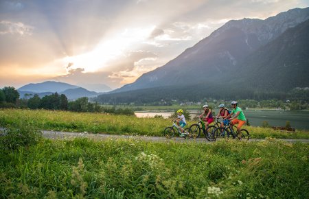 Family cycling at sunset on a trail by a mountain lake
