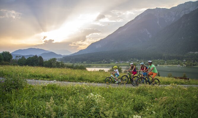 Familie auf den Mountainbiker beim Sonnenuntergang entlang des Sees