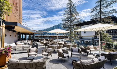 Sunny hotel terrace with lounge furniture, umbrellas and mountain view