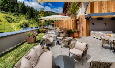 Terrassenbereich mit Hotel-Logo und gemütlichen Sitzgruppen