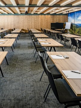 Seminar room with wooden tables, screen, daylight and nature mural