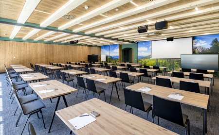 Large seminar room with screen, wooden tables and nature wall mural