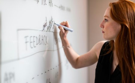 Frau schreibt mit Marker auf Whiteboard
