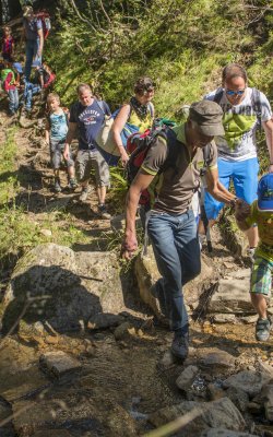 Hiking group with children on narrow forest trail