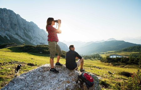 Hiking couple with binoculars on rock enjoying panoramic view