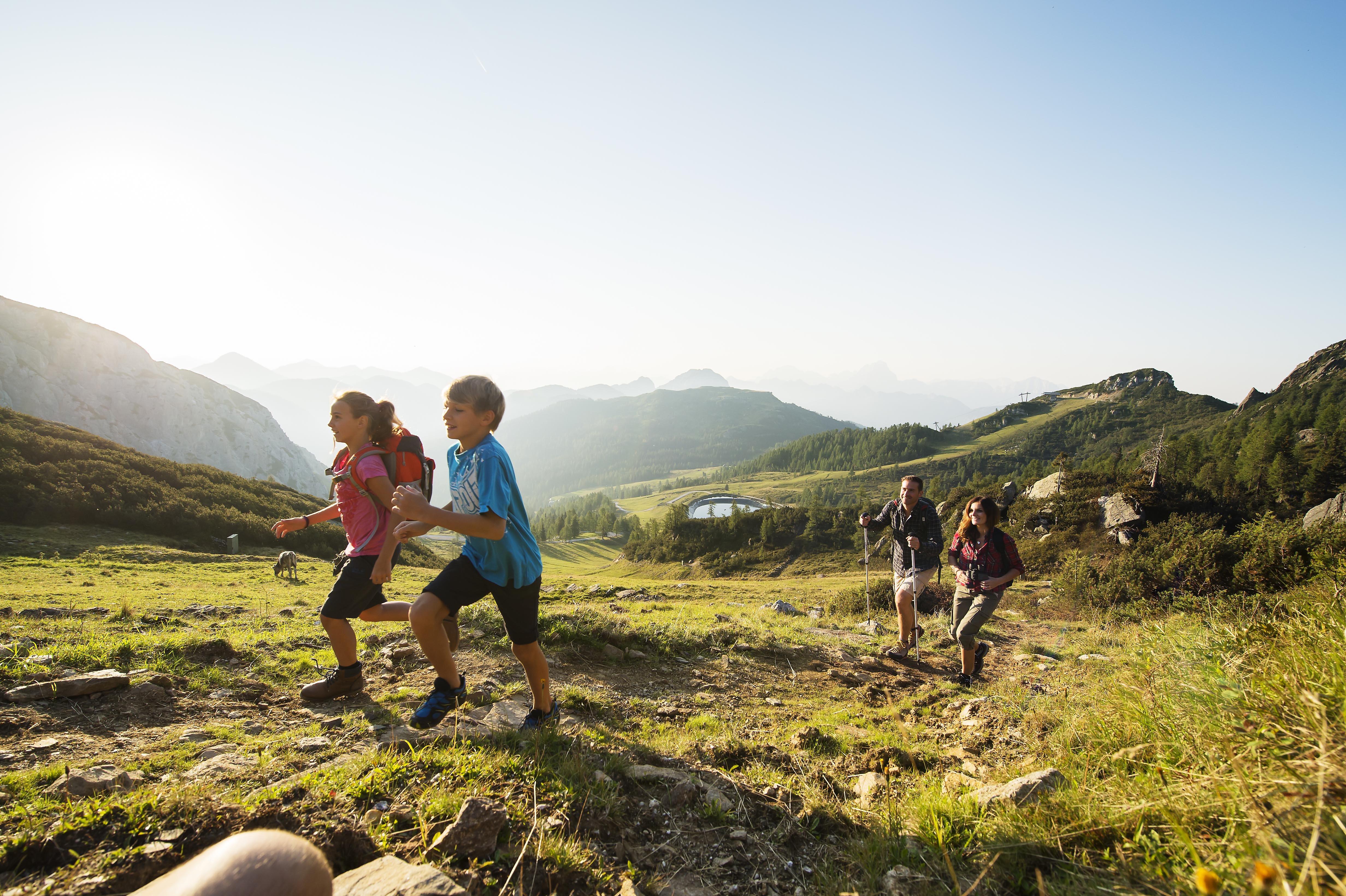Family hiking on sunny mountain trail with wide panorama