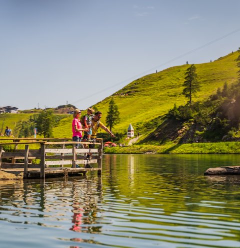 Familie auf Holzsteg an idyllischem Bergsee