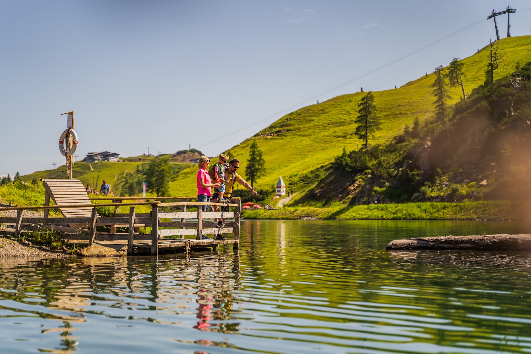 Familie auf Holzsteg an idyllischem Bergsee