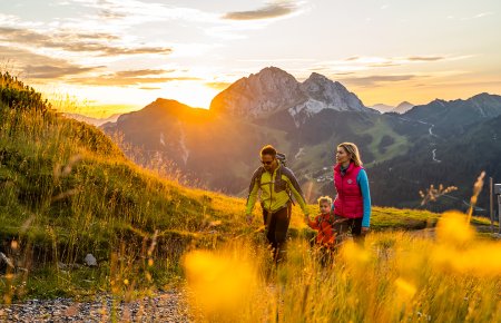 Family hiking on a mountain path at sunset