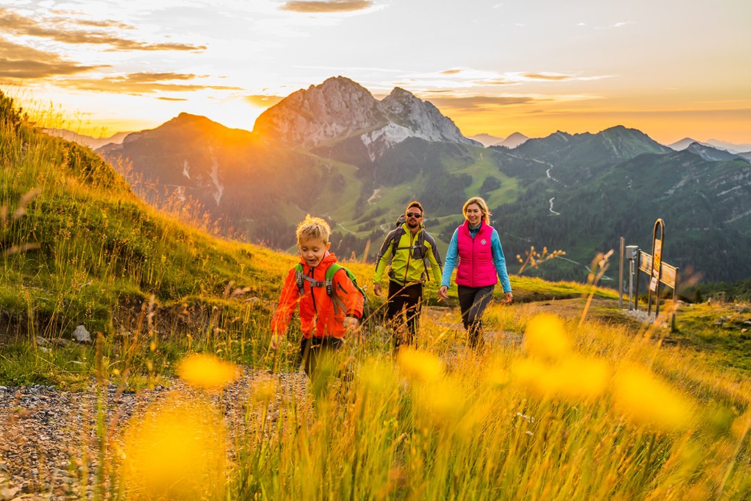 Familie beim Wandern mit Sonnenuntergang und Bergpanorama