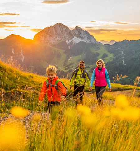 Familie beim Wandern mit Sonnenuntergang und Bergpanorama