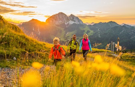 Familie beim Wandern mit Sonnenuntergang und Bergpanorama