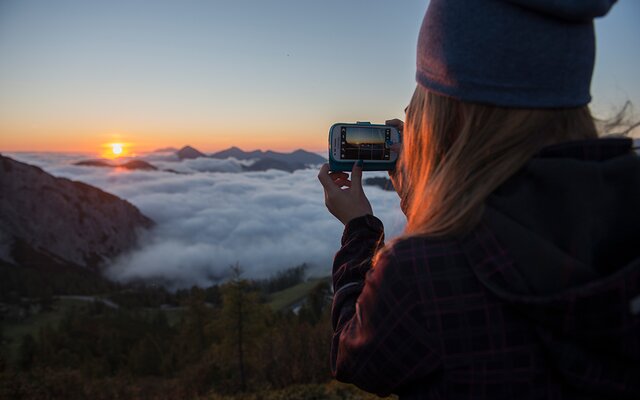 Mädchen macht Foto vom Sonnenaufgang bei der Wanderung