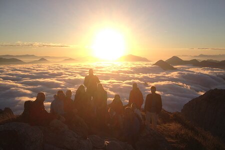 Wandergruppe beim Sonnenaufgang am Berggipfel