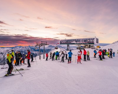 Skifahrer warten in einer Schlange vor dem Skilift während des Sonnenaufgangs.
