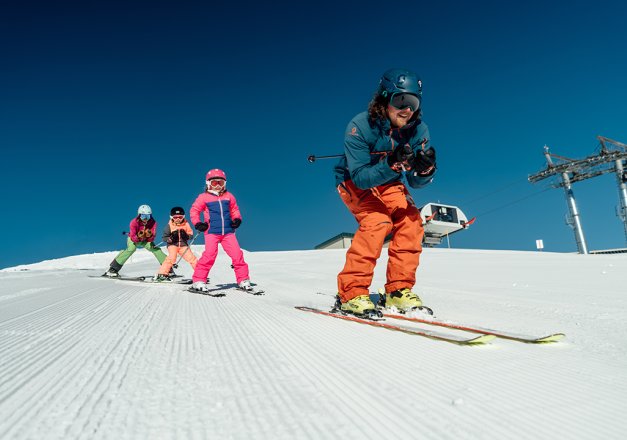 Eine Gruppe von Skifahrern fährt eine präparierte Piste hinunter.