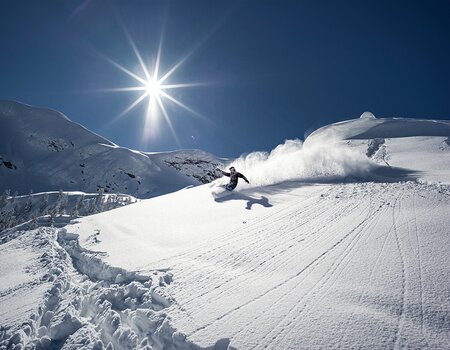 Snowboarder fahrt im Tiefschnee die Piste hinunter