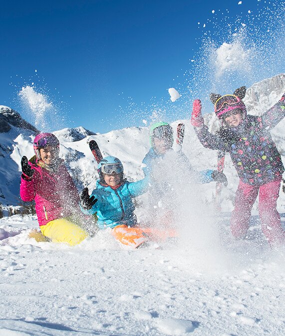 Kinder spielen und sitzen im Schnee