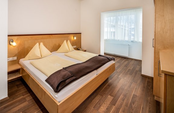 Schlafzimmer mit Doppelbett und brauner Tagesdecke