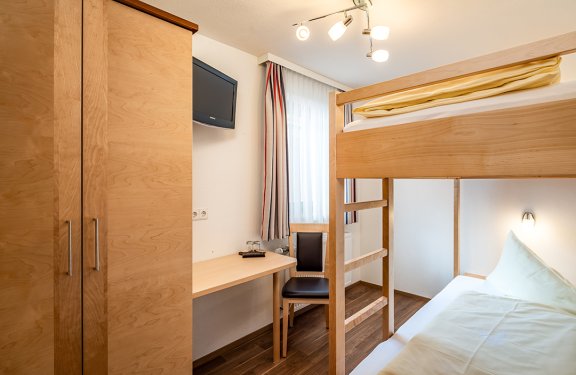 Kleines Zimmer mit Etagenbett, Schreibtisch und Fernseher